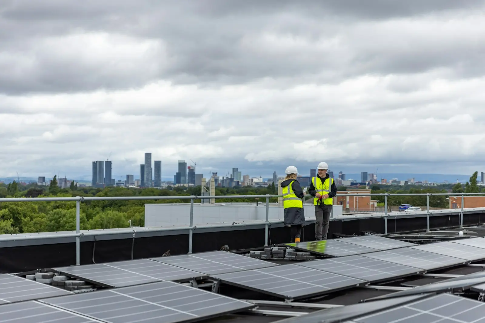 Dos técnicos sobre una cubierta con paneles solares y la ciudad al fondo